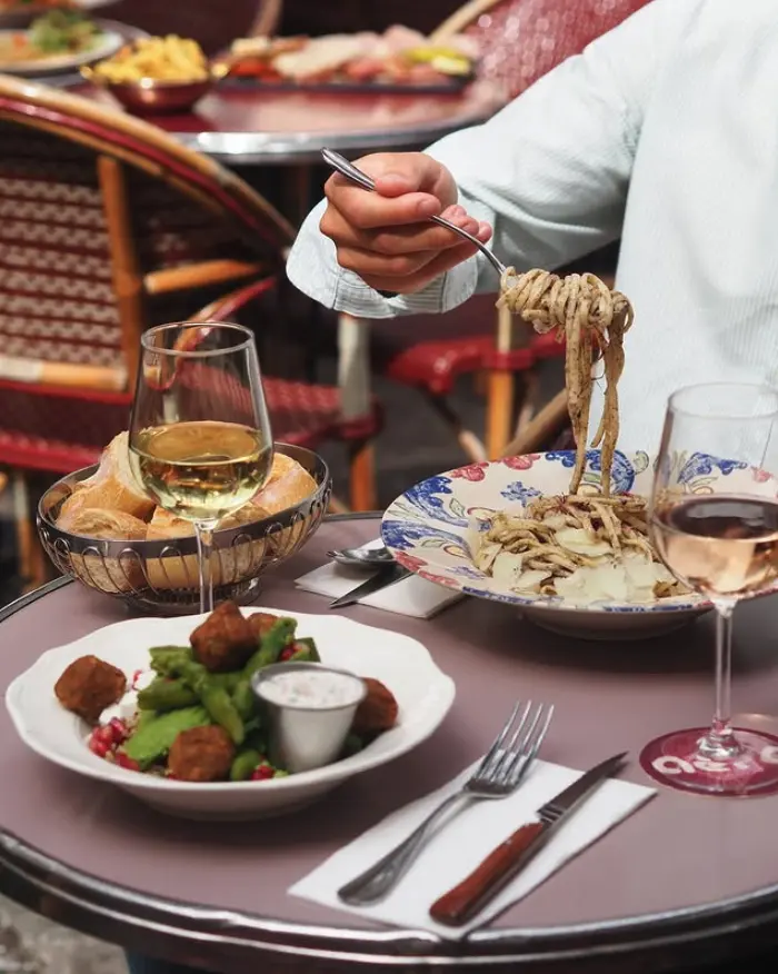 Assiette de pâtes fraîches enroulées à la fourchette et salade de falafels sur table de terrasse, restaurant Aéro Paris 16e